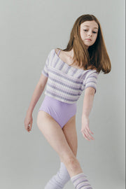 A dancer in ballet attire posing against a plain background