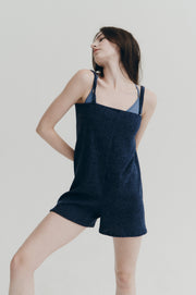 Woman wearing a navy blue romper against a plain background