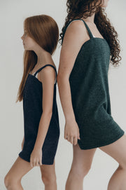 Two women wearing dark green and navy sleeveless rompers against a plain background