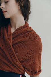 Person wearing a brown knitted shawl against a neutral background
