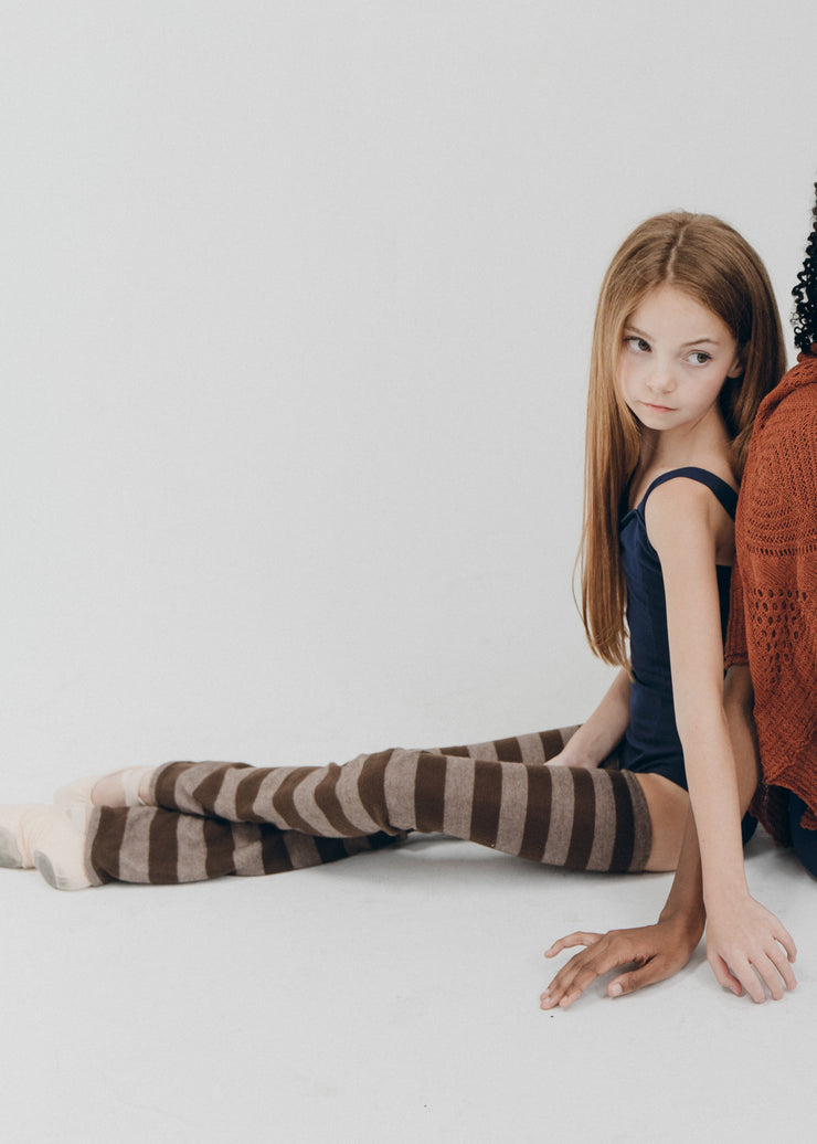 Two women sitting on a white floor in casual attire