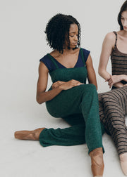Two women sitting on a white floor wearing jumpers.