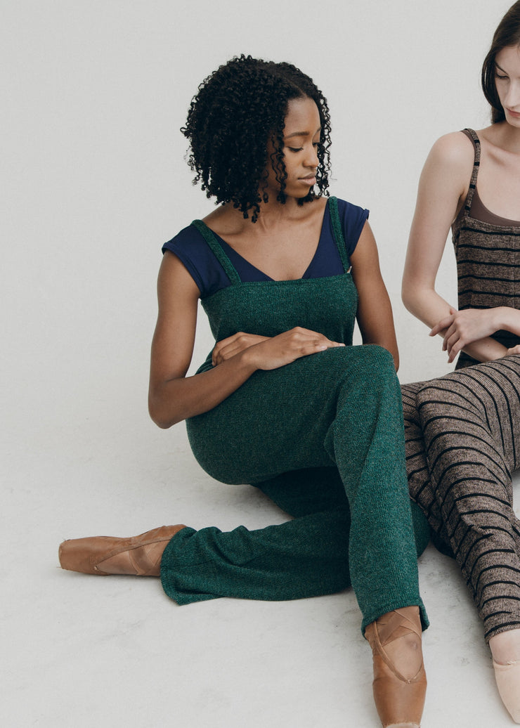Two women sitting on a white floor wearing jumpers.