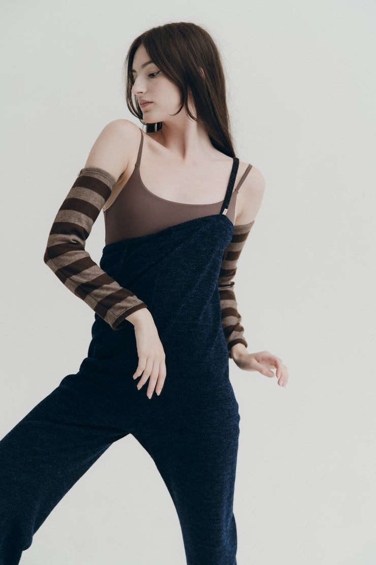 Woman wearing a dark outfit with striped sleeves against a plain background