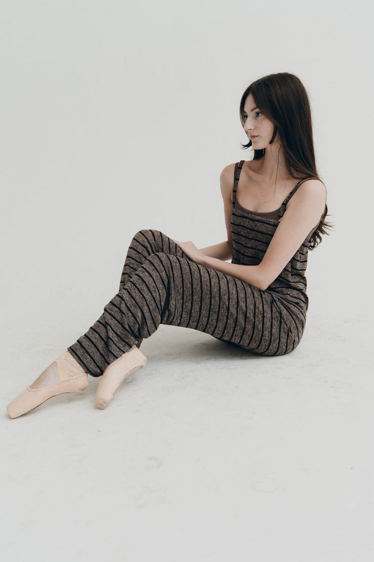 Woman wearing a striped outfit sitting on a light gray background